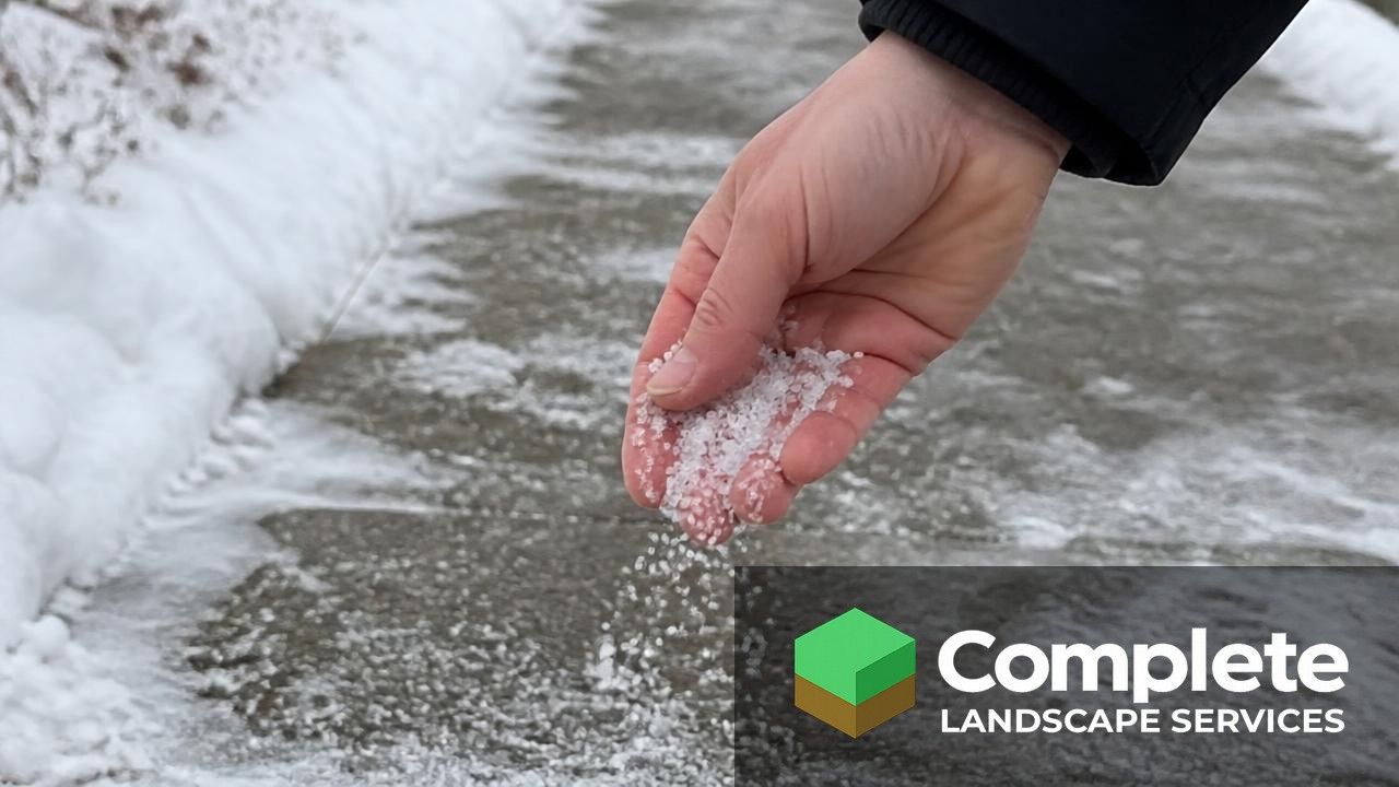 Hand spreading ice melt salt on an icy sidewalk